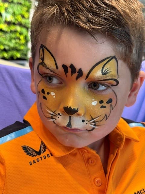Jongen met een gele tijgerkop met oren, stippen en witte snorharen