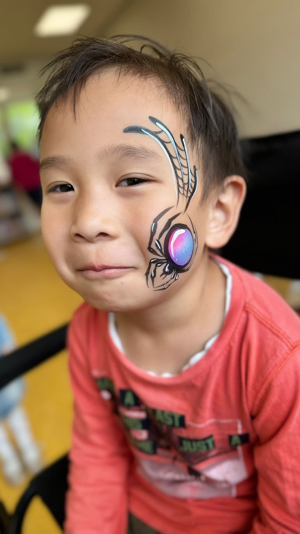 Jongen met een zwarte spin met glanzende rug en fijne weblijnen bij zijn oog