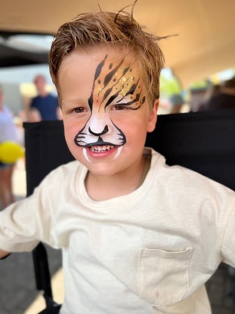 Jongen met oranje tijgerstrepen over een oog en een witte snuit met snorharen
