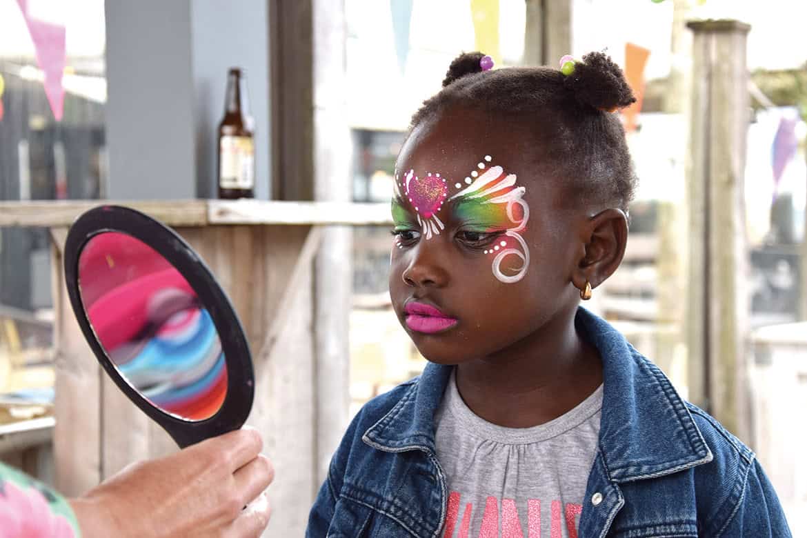 Meisje bekijkt haar regenboogkroon met roze hart in de spiegel