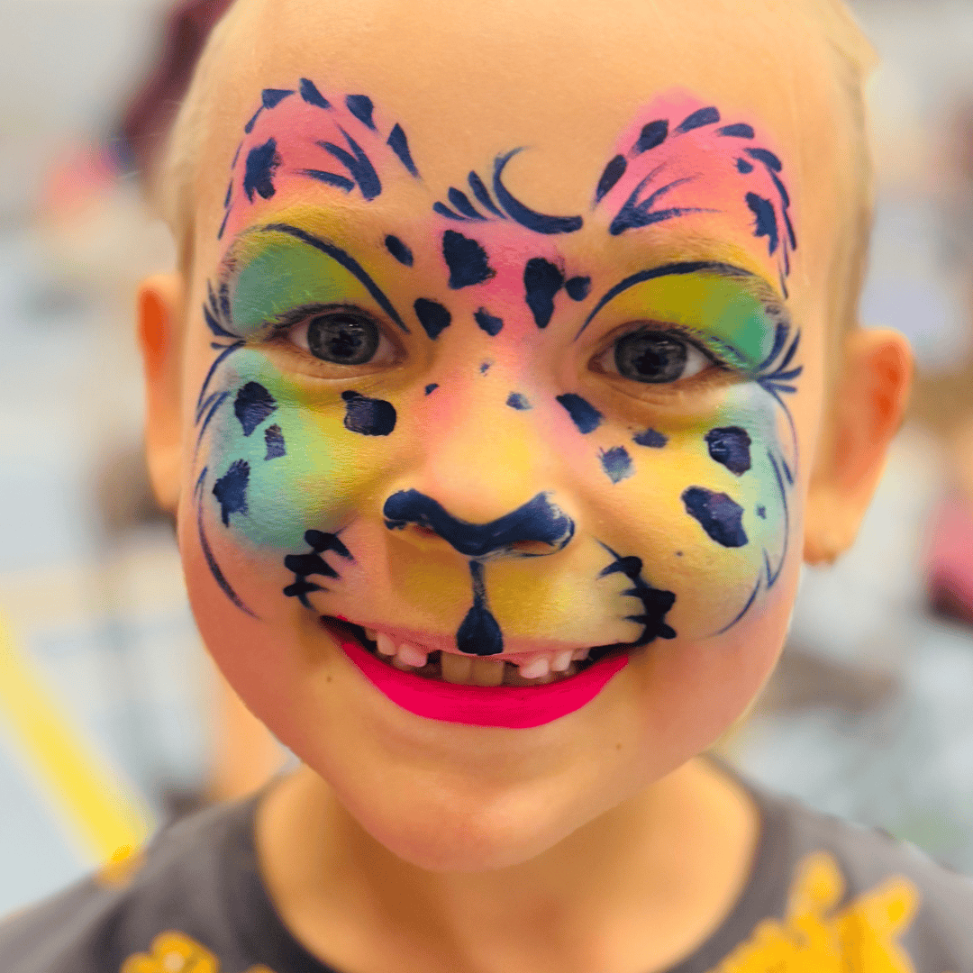 Jongen met een vrolijke tijger in regenboogkleuren over zijn hele gezicht