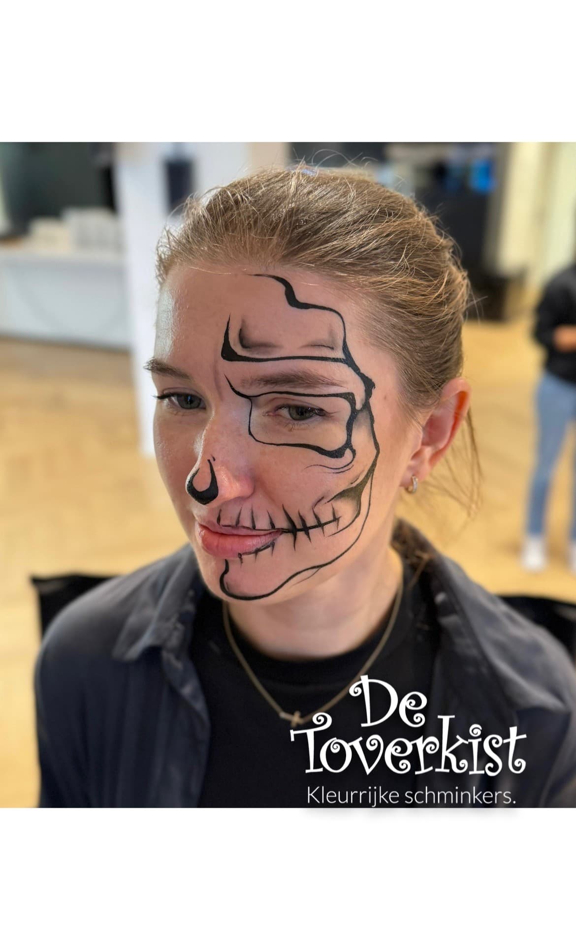 Vrouw met een schedel in enkel zwarte lijnen over haar gezicht geschminkt