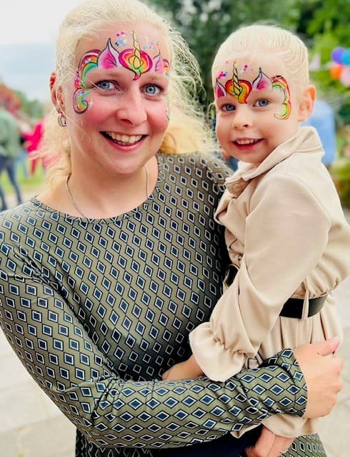Moeder en dochter met dezelfde regenboogkleurige eenhoorn op hun voorhoofd