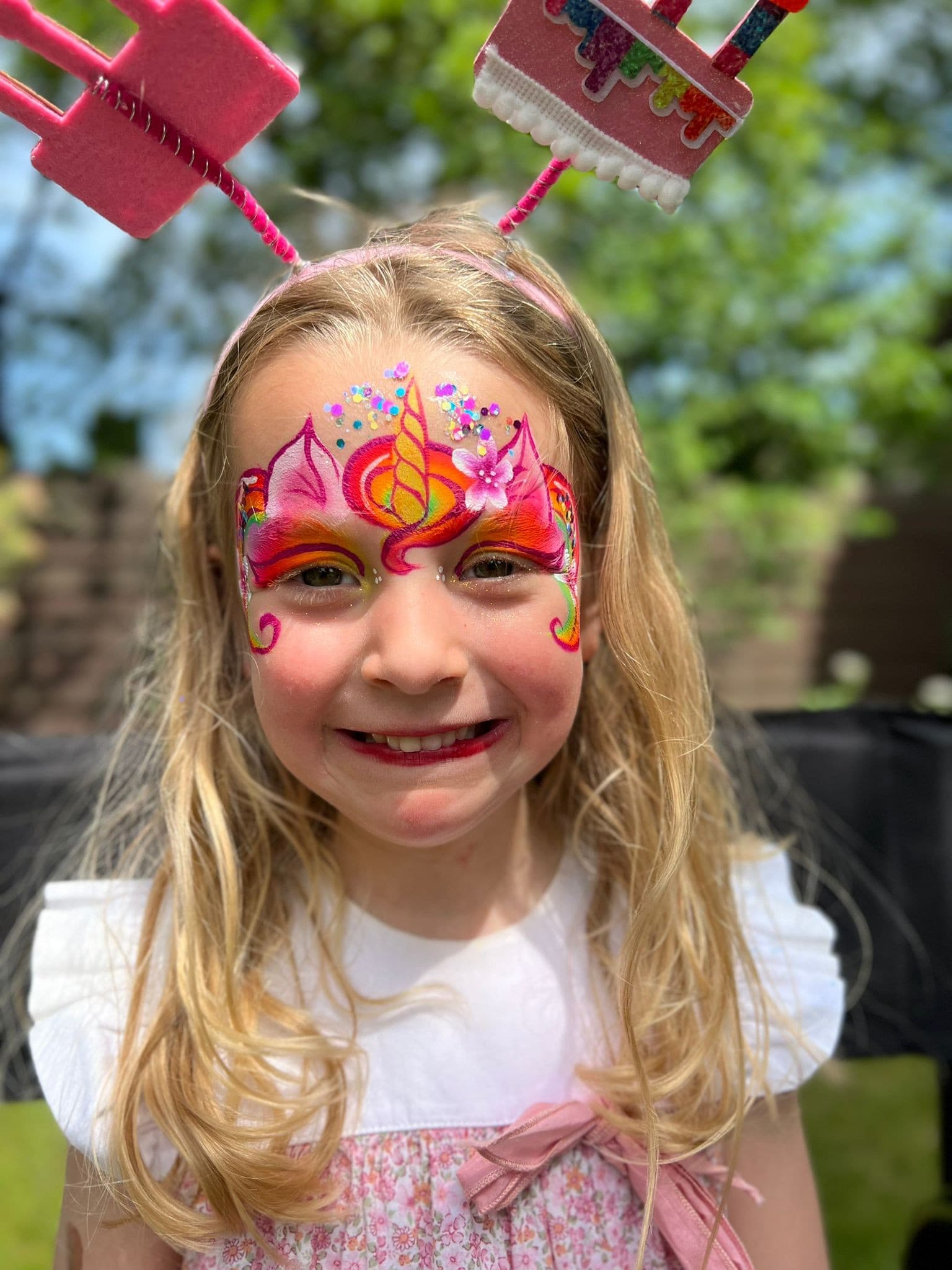Meisje met een roze eenhoorn met gouden hoorn op haar voorhoofd, buiten op een kinderfeestje
